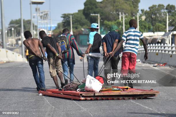 Looters carry away items in Delmas, a commune near Port-au-Prince, during protests against the rising price of fuel, on July 8, 2018. Fresh looting...