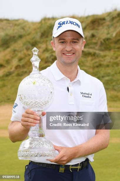 Russell Knox of Scotland poses with the trophy following his victory on the 18th green during a playoff at the end of the final round of the Dubai...