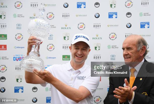Russell Knox of Scotland receives the trophy from Executive Vice Chairman & CEO of Dubai Duty Free Colm Mcloughlin following his victory on the 18th...