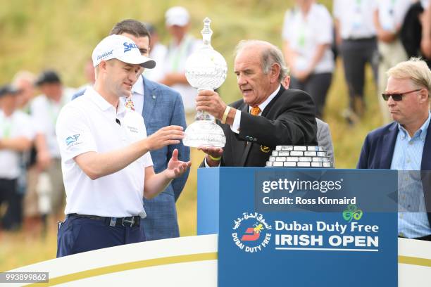 Russell Knox of Scotland receives the trophy from Executive Vice Chairman & CEO of Dubai Duty Free Colm Mcloughlin following his victory on the 18th...