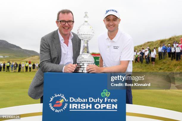 Russell Knox of Scotland poses with the trophy and Chief Executive of the Rory foundation Barry Funston following his victory on the 18th green...