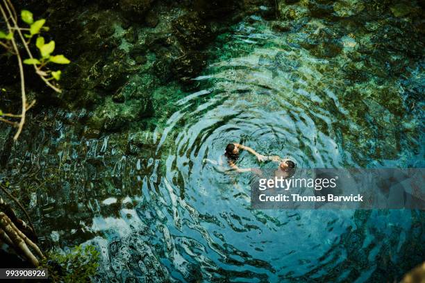 overhead view of couple holding hands while swimming in cenote during vacation - ideal wife stock pictures, royalty-free photos & images