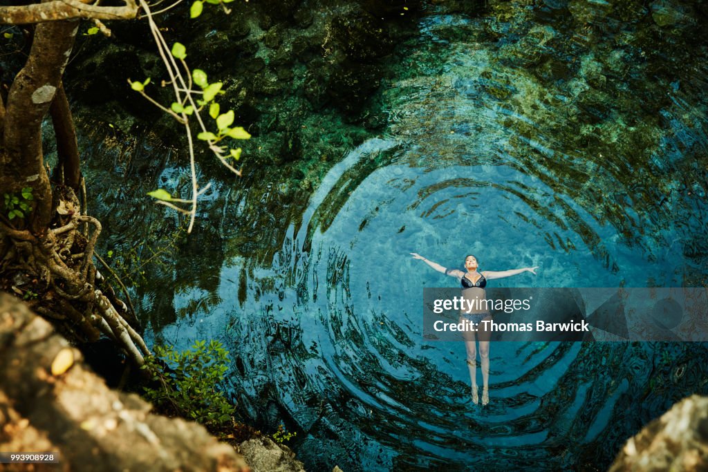 Overhead view of woman floating on back in cenote while on vacation