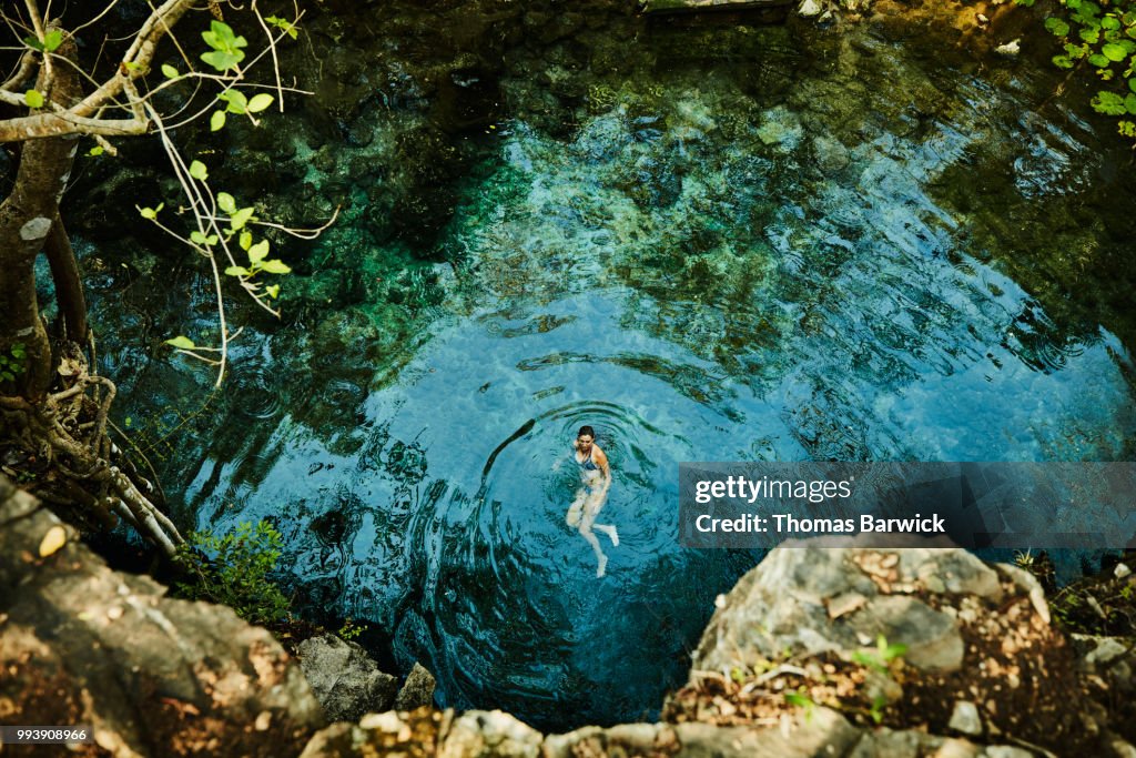 Overhead view of woman swimming in cenote while on vacation