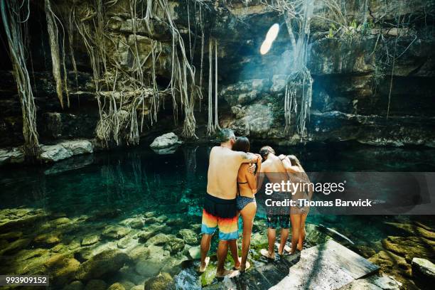 embracing family preparing to swim in cenote during vacation - preteen girl no shirt stock pictures, royalty-free photos & images