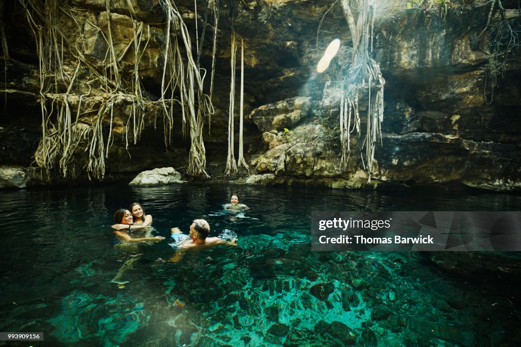 Smiling family swimming together while exploring cenote during vacation