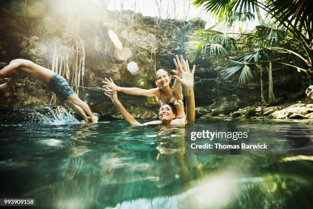 smiling daughter sitting on mothers shoulders while swimming together with family in cenote - cenote bildbanksfoton och bilder