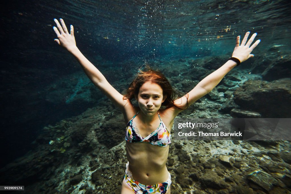 Underwater view of smiling girl holding breath while swimming underwater