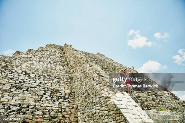 gay couple taking selfie with smartphone while exploring mayan ruins during vacation - ruined clothes stock pictures, royalty-free photos & images