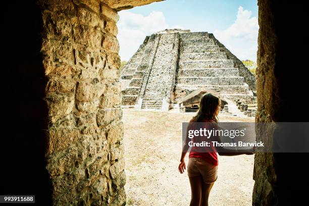 girl walking through doorway while exploring mayapan ruins during vacation - off the beaten path foto e immagini stock