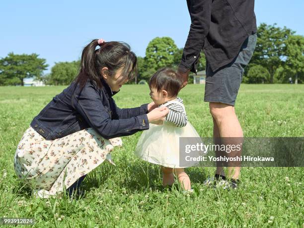 toddler girl ( 6-11 months ) learn to walk on lawn at park under sunshine - stadtteil koto stock-fotos und bilder
