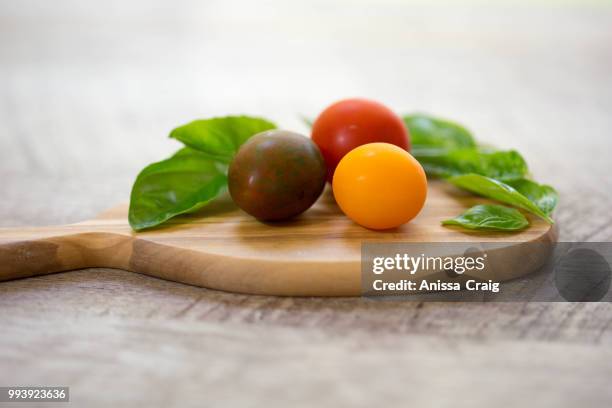 baby heirloom tomatoes with fresh basil - yellow tomato stock pictures, royalty-free photos & images