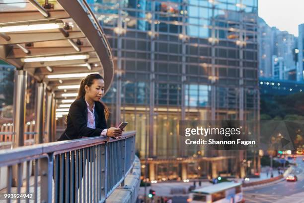 business woman standing on pedestrian bridge at dusk - pedestrian overpass stock pictures, royalty-free photos & images
