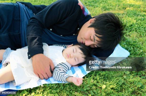 father helping infant girl ( 6-11 months )  crawl at park under sunshine - stadtteil koto stock-fotos und bilder