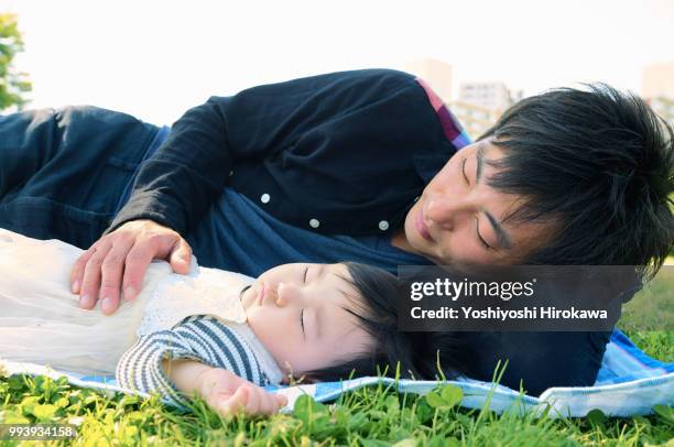 father helping infant girl ( 6-11 months )  crawl at park under sunshine - stadtteil koto stock-fotos und bilder