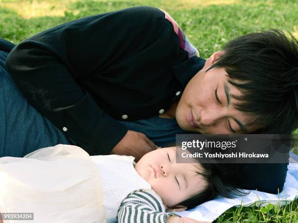 father helping infant girl ( 6-11 months )  crawl at park under sunshine - stadtteil koto stock-fotos und bilder