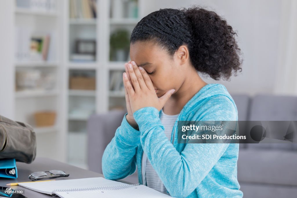 Adolescente se trouve en face de devoirs avec la tête dans les mains