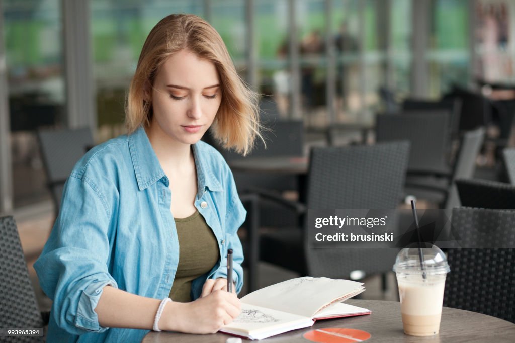 A young attractive woman of 20 years draws in a sketchbook