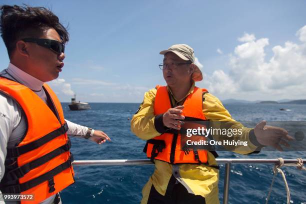 Chinese rescue expert volunteer and a diver from a Thai diving center discuss search plans on the fourth day of rescue operation of capsized tourist...