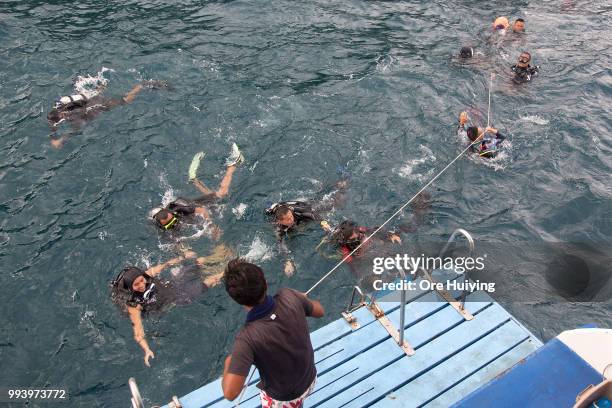 Team of volunteers made up of Chinese rescue experts and divers from a Thai diving center emerge from the water after a search on the fourth day of...