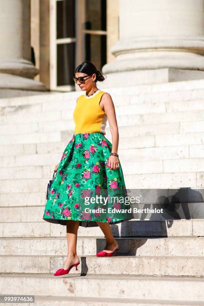 Giovanna Battaglia wears a yellow sleeveless top, a green flower print skirt, a bag, pink shoes, outside Fendi, during Paris Fashion Week Haute...