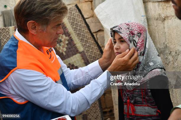 Turkish-American cardiothoracic surgeon Mehmet Oz examines Syrian Zeynep , who has a hole in her heart, during his visit in Azaz, Syria on July 8,...