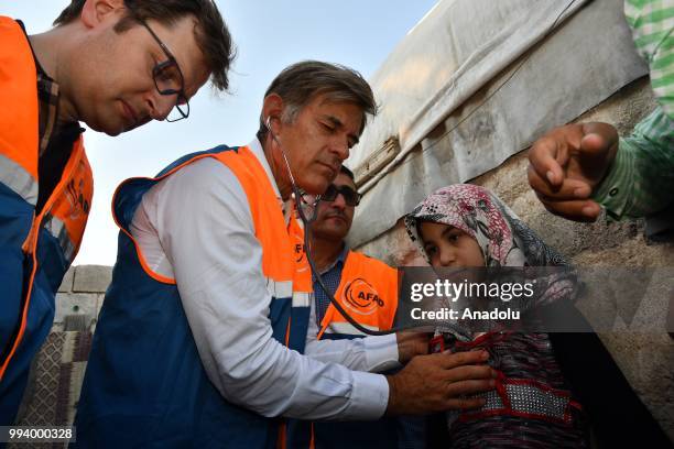 Turkish-American cardiothoracic surgeon Mehmet Oz examines Syrian Zeynep , who has a hole in her heart, during his visit in Azaz, Syria on July 8,...