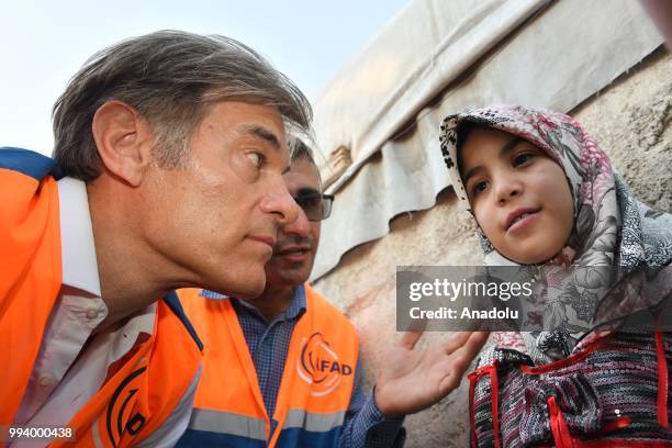 Turkish-American cardiothoracic surgeon Mehmet Oz examines Syrian Zeynep , who has a hole in her heart, during his visit in Azaz, Syria on July 8,...