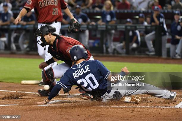 Carlos Asuaje of the San Diego Padres slides safely into home on a double by teammate Eric Hosmer during the first inning as Jeff Mathis of the...