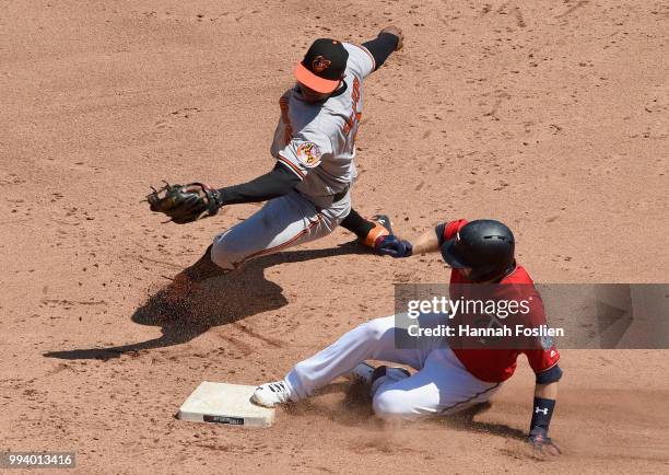 Brian Dozier of the Minnesota Twins slides in safely with a double as Jonathan Schoop of the Baltimore Orioles applies a tag during the sixth inning...