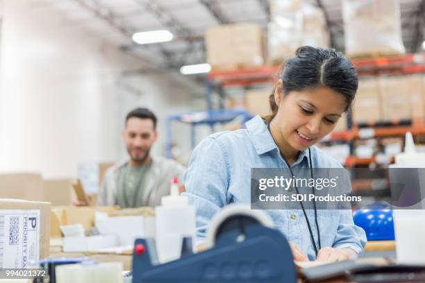 mujer concentra mientras trabajaba en el almacén de distribución - oficina de correos fotografías e imágenes de stock