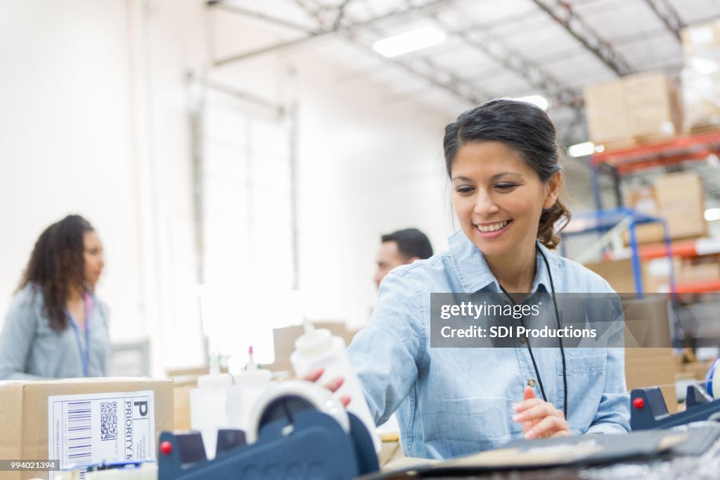 Cheerful woman prepares package in distribution warehouse