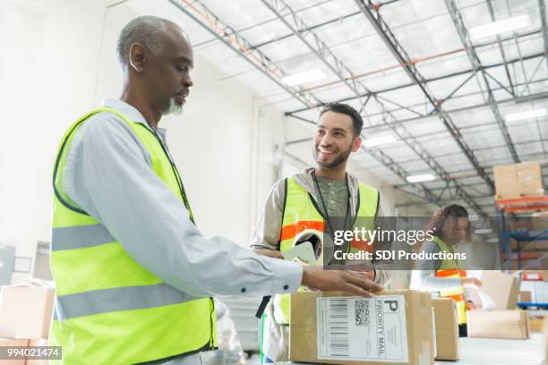 male distribution warehouse employees working together - tape dispenser stock pictures, royalty-free photos & images