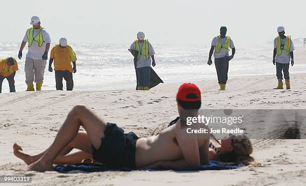 Workers search the beach for tar balls to be picked up as they wash ashore from the Deepwater Horizon site on May 14, 2010 in Dauphin Island,...