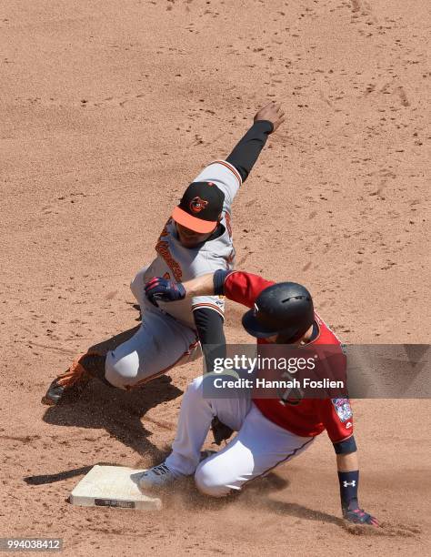 Brian Dozier of the Minnesota Twins slides in safely to second base with a double as Jonathan Schoop of the Baltimore Orioles applies a tag during...