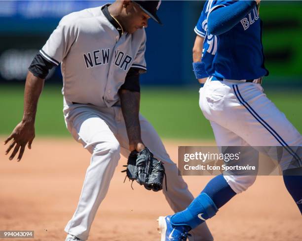 New York Yankees Pitcher Domingo German fields a ball on an error by teammate First baseman Greg Bird to try to get Toronto Blue Jays Infield Devon...