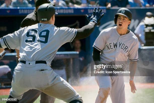 New York Yankees Infielder Tyler Wade slides home safe to get the go ahead run as teammate Outfielder Aaron Judge welcomes him during the MLB game...