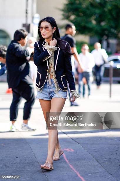 Guest wears a military jacket, blue denim shorts, sandales shoes, clear sunglasses , outside Fendi, during Paris Fashion Week Haute Couture Fall...
