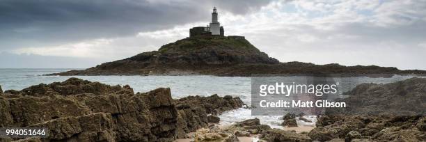 landscape panorama of mumbles lighthouse in wales with sunbeams - mumbles stock-fotos und bilder