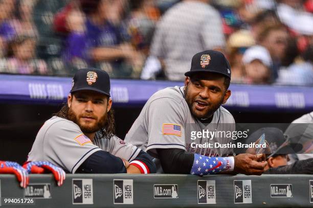 Brandon Crawford and Pablo Sandoval of the San Francisco Giants look out from the dugout before a game against the Colorado Rockies at Coors Field on...