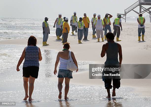 Workers search the beach for tar balls to be picked up as they wash ashore from the Deepwater Horizon site on May 14, 2010 in Dauphin Island,...