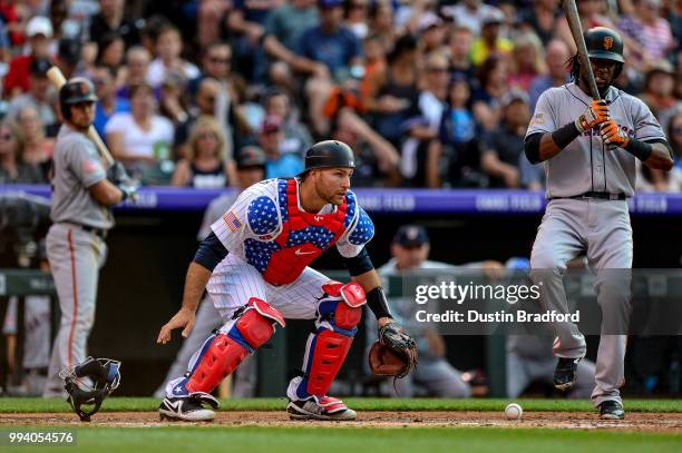 Chris Iannetta of the Colorado Rockies takes off his catchers mask and looks to cover a blocked ball as Alen Hanson of the San Francisco Giants bats...