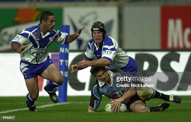 Mat Rogers of the Sharks beats Craig Polla-Mounter and Darren Smith of the Bulldogs to score a try during the round 25 NRL match between the Bulldogs...