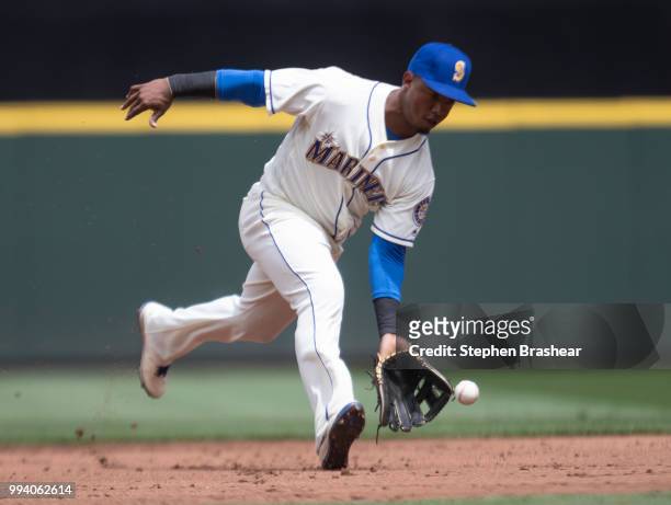 Shortstop Jean Segura of the Seattle Mariners fields a ground ball hit by Ian Desmond of the Colorado Rockies before throwing first base for an out...