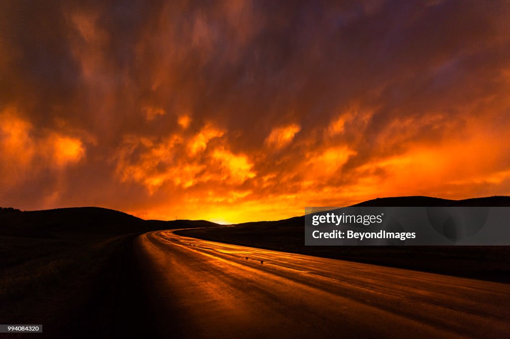 Nassen feurige rote Autobahn reflektierenden Wolken bei Sonnenuntergang in South Dakota