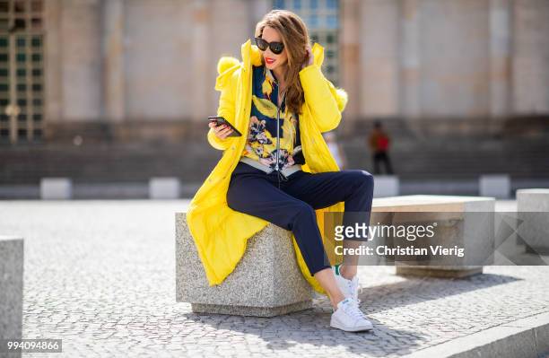Alexandra Lapp is seen wearing a blouson jacket with floral print, blue drawstring pants and a bright yellow duffle coat with a yellow fur hood from...