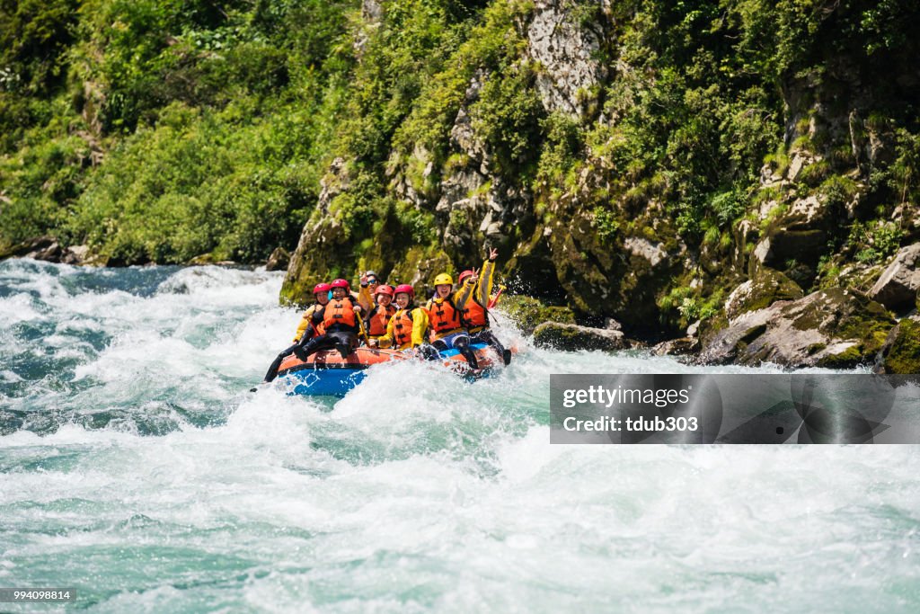 Small group of men and women white water river rafting