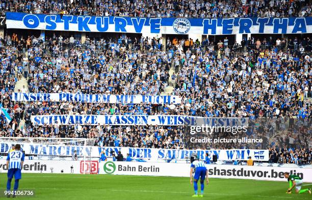 Fans of Hertha hold up banners reading: "Unser Problem mit Euch: Schwarze Kassen, Weiße Weste. Das Märchen von der sauberen WM" during the German...