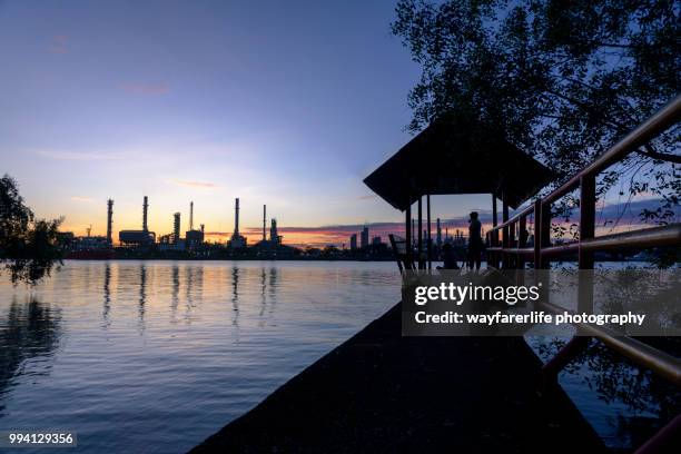 oil refinery plant and its reflection over water surface at sunrise - 反射用池 ストックフォトと画像