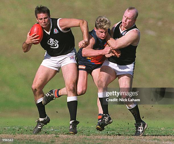 Laine Spencer and Lee Urquhart of the Western Suburbs sandwich Ben Physick of the Eagles during the Sydney AFL match between the East Coast Eagles...